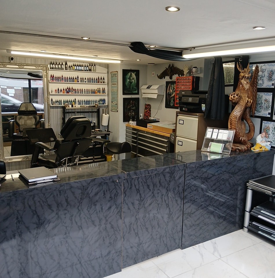 Dimly lit tattoo studio with red rim light and tattoo machine
